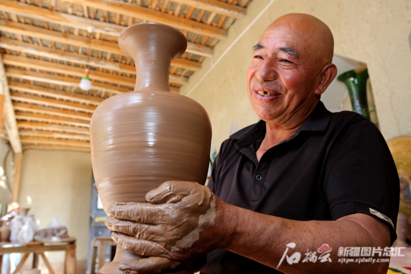 6月19日，英吉沙縣芒辛鎮(zhèn)恰克日庫(kù)依村土陶非遺傳承人阿卜杜熱合曼·麥麥提敏在欣賞剛制作的土陶作品。石榴云/新疆日?qǐng)?bào)記者 蔡增樂(lè) 攝