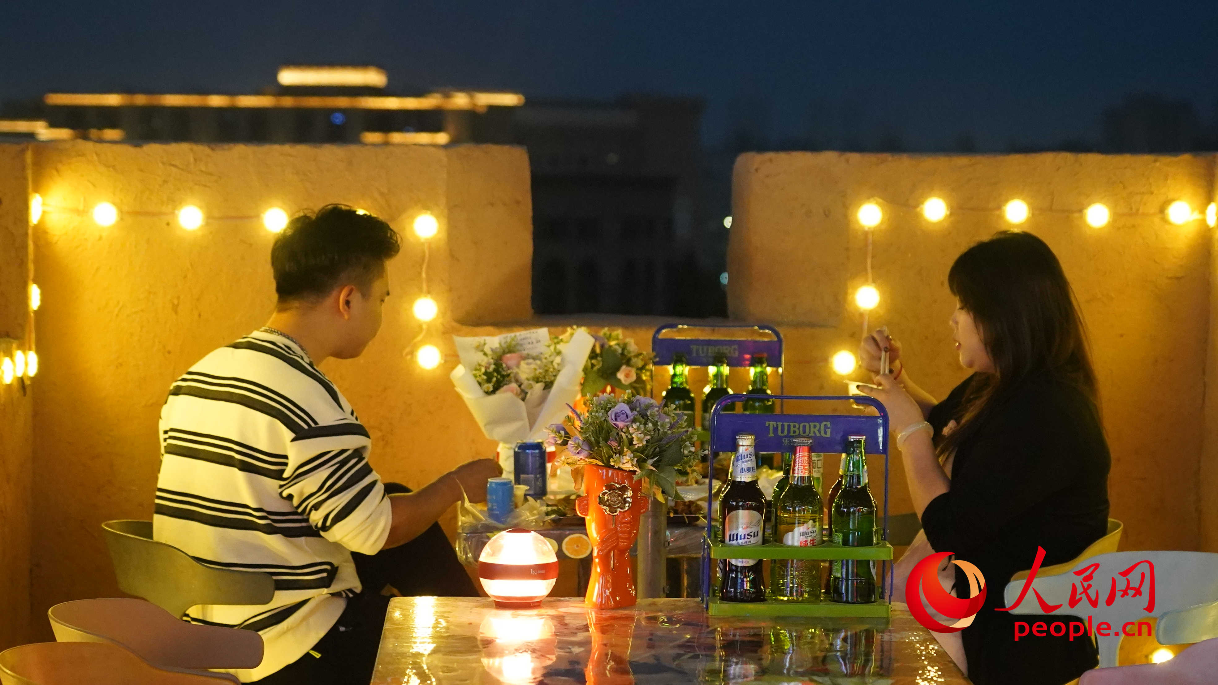 夜晚的古城燈火璀璨，一對(duì)情侶正在享用美食。人民網(wǎng) 李龍攝